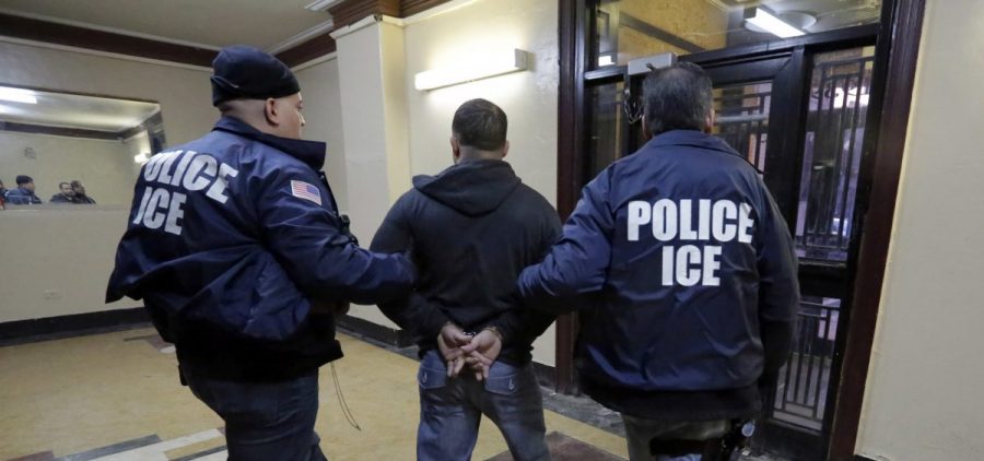 In this March 3, 2015, photo, Immigration and Customs Enforcement officers escort an arrestee in an apartment building in the Bronx borough of New York during a series of early morning raids.