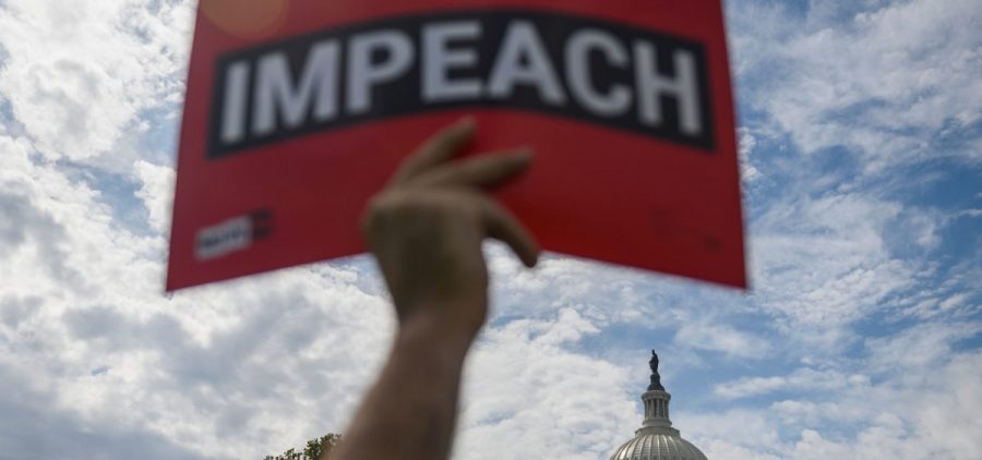 A protester holds up a sign in favor of impeachment outside the U.S. Capitol building on Thursday.
