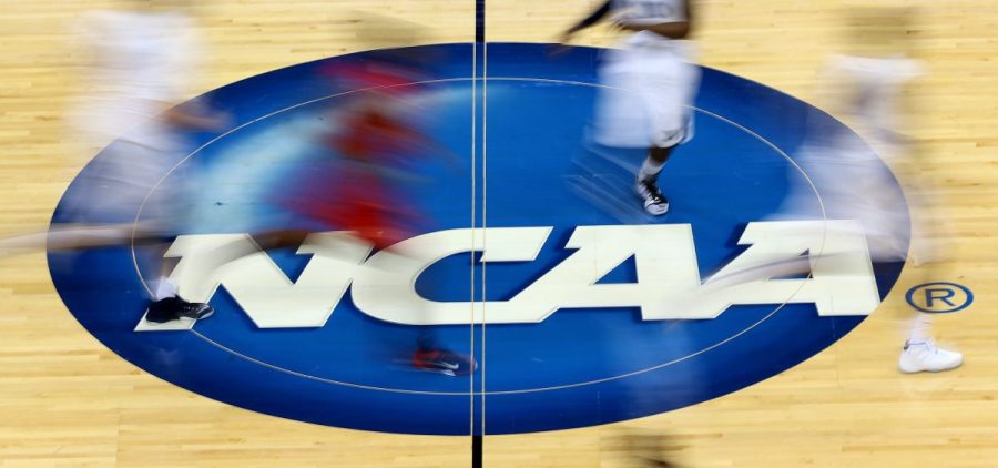 The NCAA logo stands at mid-court during the 2015 NCAA Division I men's basketball tournament, an event that annually rakes in significant revenue for the organization. In a major reversal Tuesday, the governing body signaled it would allow compensation for college athletes.