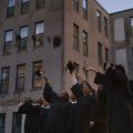 college graduates tossing caps in front of prison