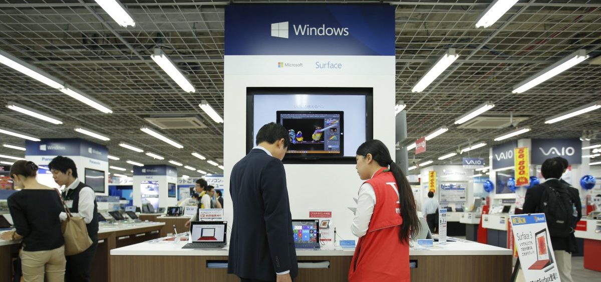 A sales clerk speaks with a customer in front of Microsoft Corp.'s display at an electronics store in Tokyo. Microsoft's division in Japan says it saw productivity grow by 40% after allowing employees to work for four days a week rather than five.