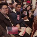 Newly sworn-in United States citizens are all smiles and waving flags during a naturalization ceremony