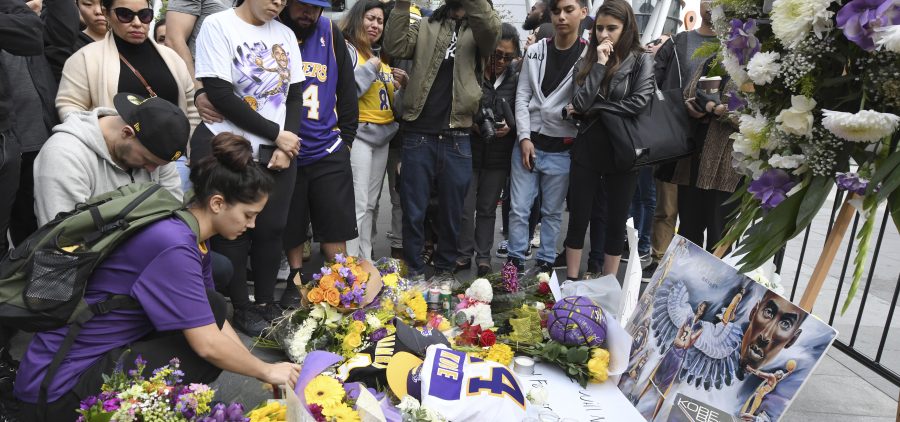 Valerie Samano, left, places flowers at a memorial near the Staples Center in Los Angeles, after the death of Laker legend Kobe Bryant on Sunday.