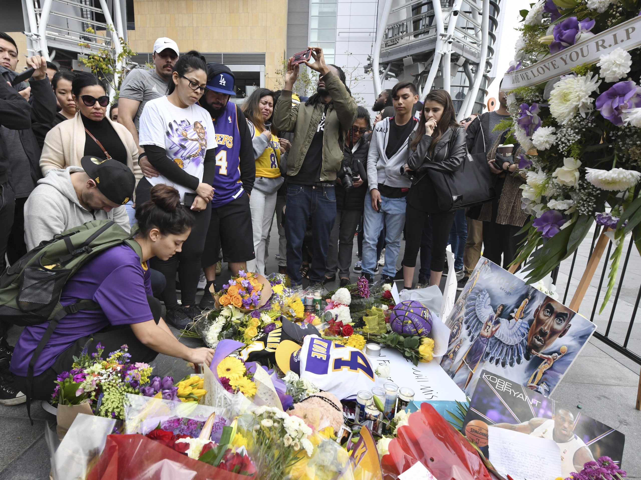 Valerie Samano, left, places flowers at a memorial near the Staples Center in Los Angeles, after the death of Laker legend Kobe Bryant on Sunday.