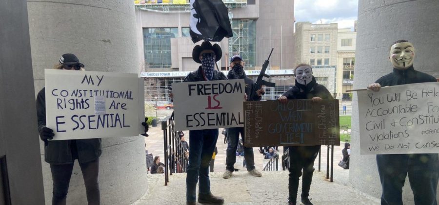 About 75 people wearing masks and carrying signs protest outside the Ohio Statehouse on Thursday, April 9, 2020, in Columbus, Ohio.