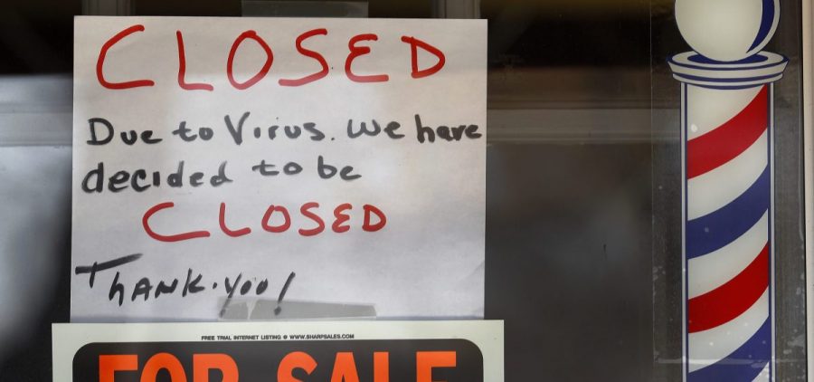 Signs are displayed in the window of a store in Grosse Pointe Woods, Mich. The Paycheck Protection Program, aimed at helping small businesses survive the coronavirus crisis, has been beset by problems.