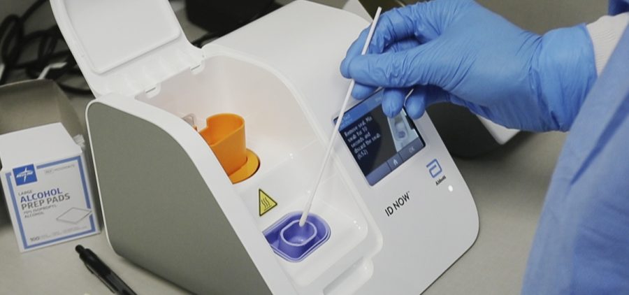 A lab technician dips a sample into an Abbott Laboratories ID Now testing machine at the Detroit Health Center on April 10.
