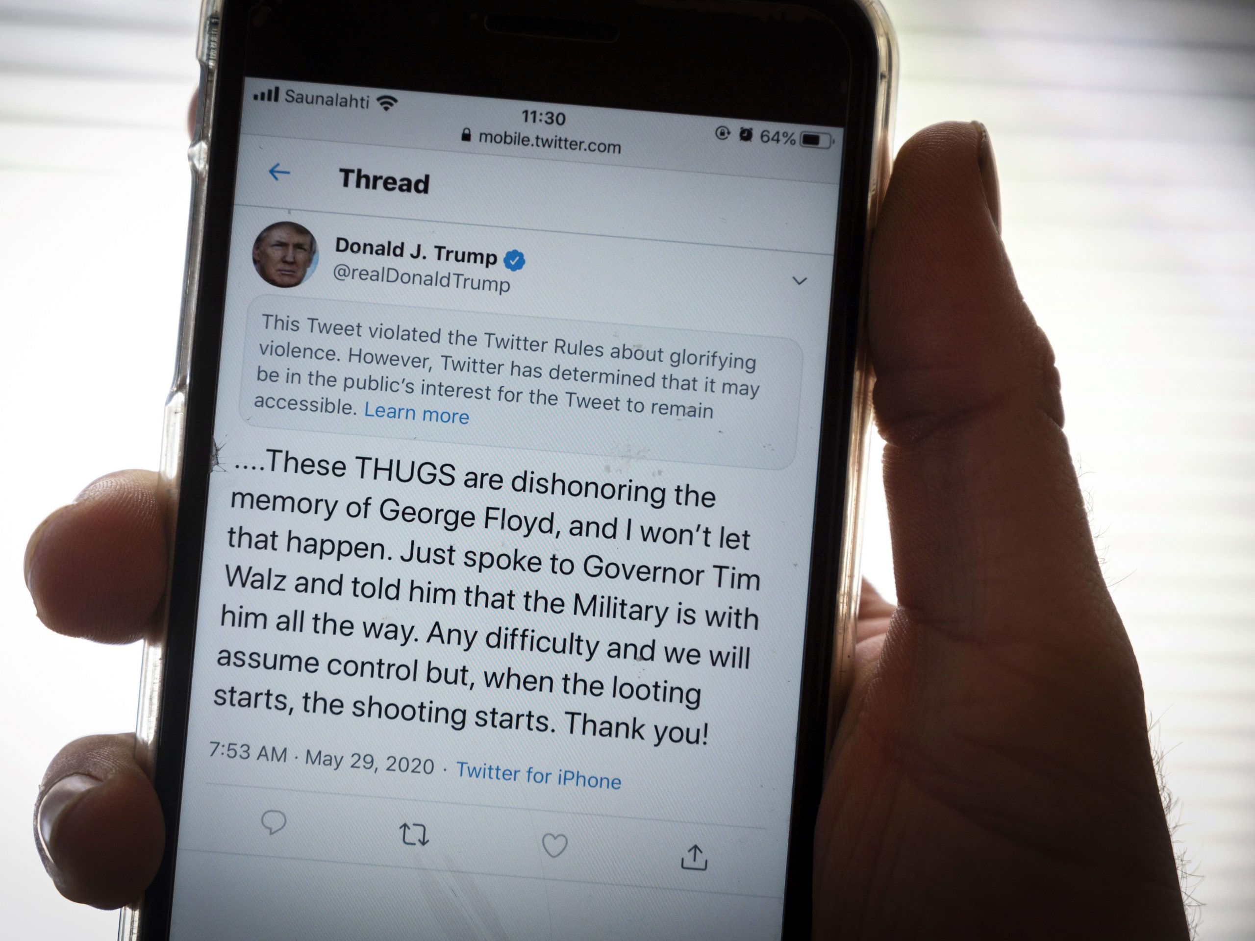 President Trump's Twitter page is displayed on a mobile phone. The social media company flagged one of his tweets about Minneapolis as "glorifying violence" and hid it from public view unless a user clicks on it.