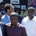 All four former Minneapolis police officers now face criminal charges in the death of George Floyd. Attorney Ben Crump, left, escorts Floyd's son Quincy Mason, second from left, on Wednesday during a visit to the memorial where Floyd was arrested in Minneapolis.