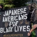 two protestors holding sign that says Japanese Americans for Black Lives
