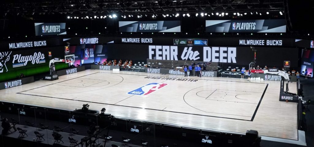 Officials stand beside an empty court at the scheduled start of an NBA basketball first round playoff game between the Milwaukee Bucks and the Orlando Magic, Wednesday, Aug. 26, 2020, in Lake Buena Vista, Fla.