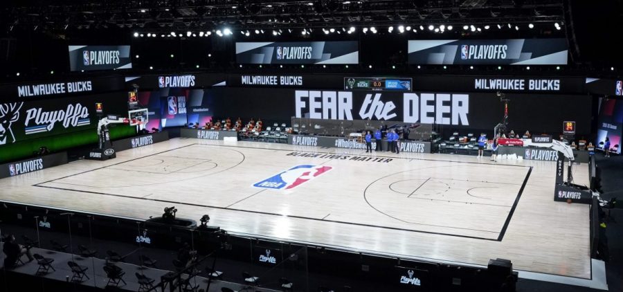 Officials stand beside an empty court at the scheduled start of an NBA basketball first round playoff game between the Milwaukee Bucks and the Orlando Magic, Wednesday, Aug. 26, 2020, in Lake Buena Vista, Fla.