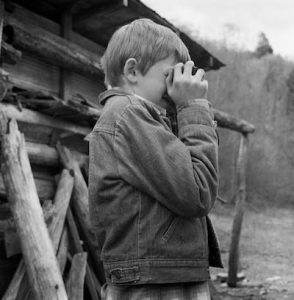 black and white of young boy looking through cameera viewfinder