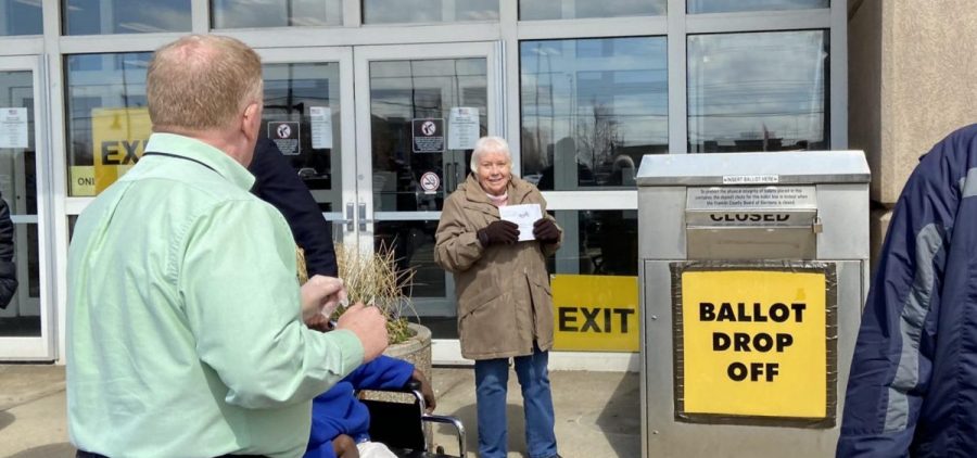 A voter shows her absentee ballot to Franklin County Board of Elections Director Ed Leonard (left) before putting it in the ballot drop box on the last day of weekend early voting before the March 2020 primary.