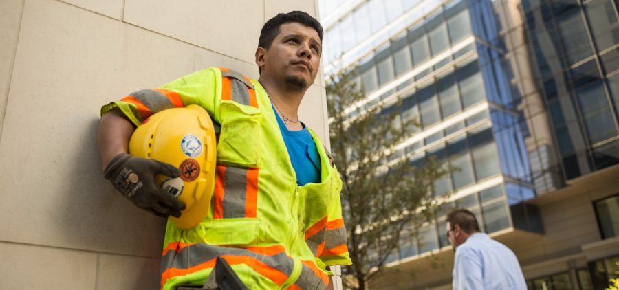 Electrical worker in vest leaning against building