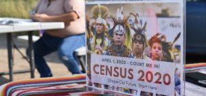 A sign promoting participation in the 2020 census is displayed as Selena Rides Horse enters information into a phone for a member of the Crow Indian Tribe in Lodge Grass, Mont., in August.