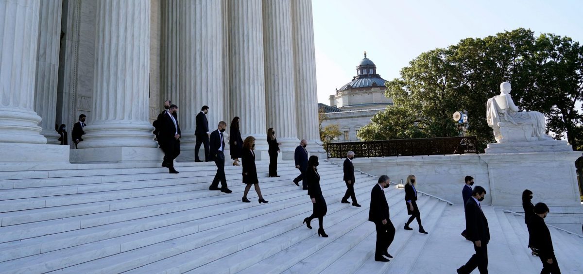 Former law clerks for Justice Ruth Bader Ginsburg stand on the steps of the Supreme Court as they await the arrival of the casket of Ginsburg on Wednesday.