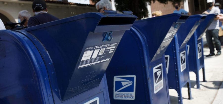 A customer deposits mail into a U.S. Postal Service mail collection box this week in Burbank, Calif.