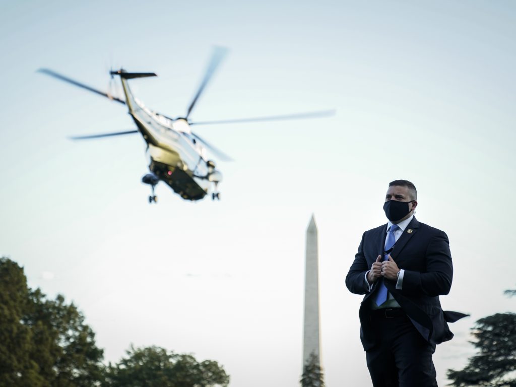 A U.S. Secret Service agent stands on the South Lawn of the White House as Marine One, with the president on board, leaves Friday for Walter Reed.