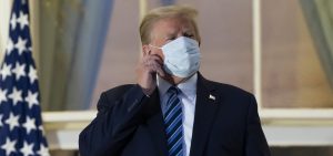 President Donald Trump removes his mask as he stands on the Blue Room Balcony upon returning to the White House Monday, Oct. 5, 2020, in Washington, after leaving Walter Reed National Military Medical Center, in Bethesda, Md. Trump announced he tested positive for COVID-19 on Oct. 2.