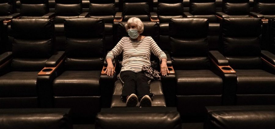 A woman sits in a theater in Irvine, Calif., waiting for a movie to start, on Sept. 8. A COVID-19 vaccine could unleash pent-up spending from households that have mostly avoided activities like going to the gym during the coronavirus pandemic.