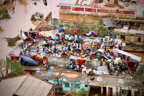 People gather on the roof of a house submerged by floods in Buzi