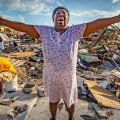 Aliana Alexis of Haiti stands on the concrete slab of what is left of her home