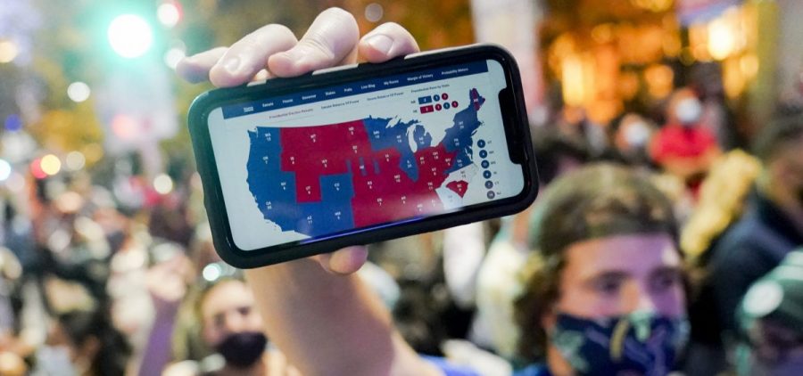 A supporter of President-elect Joe Biden holds up his mobile phone to display the Electoral College map outside the Philadelphia Convention Center after the 2020 presidential election is called on Nov. 7.