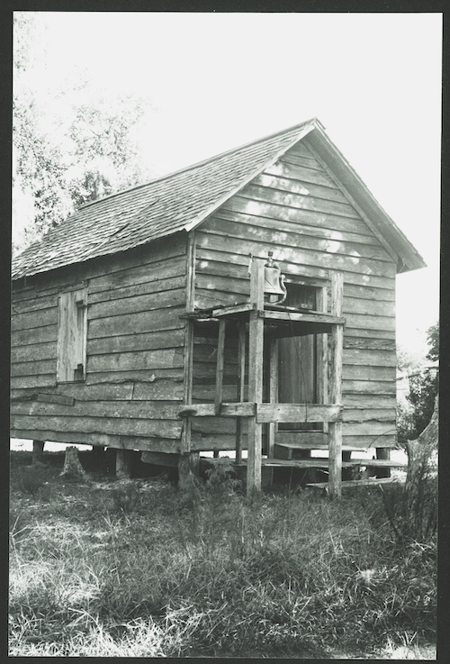 Praise house at Sapelo, a rustic cabin type structure used as a church with a bell in front.