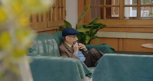 elderly man sitting on couch (from a distance)