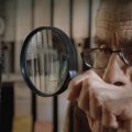 elderly man looking through magnifying glass