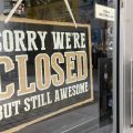A closed sign hangs in the window of a business