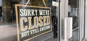 A closed sign hangs in the window of a business