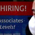 A man walks past a "Now Hiring" sign in front of a store in early December in Arlington, Va. U.S. employers added 379,000 jobs in February, as hiring picked up sharply from the previous month.