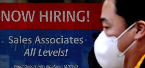 A man walks past a "Now Hiring" sign in front of a store in early December in Arlington, Va. U.S. employers added 379,000 jobs in February, as hiring picked up sharply from the previous month.