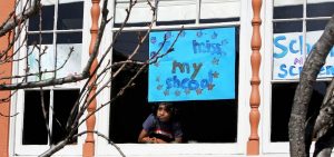 Jeevan Guha, 6, poses for a portrait near his homemade sign in San Francisco. His sign reads, "I miss my school."