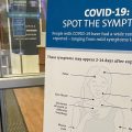 A sign lists COVID symptoms