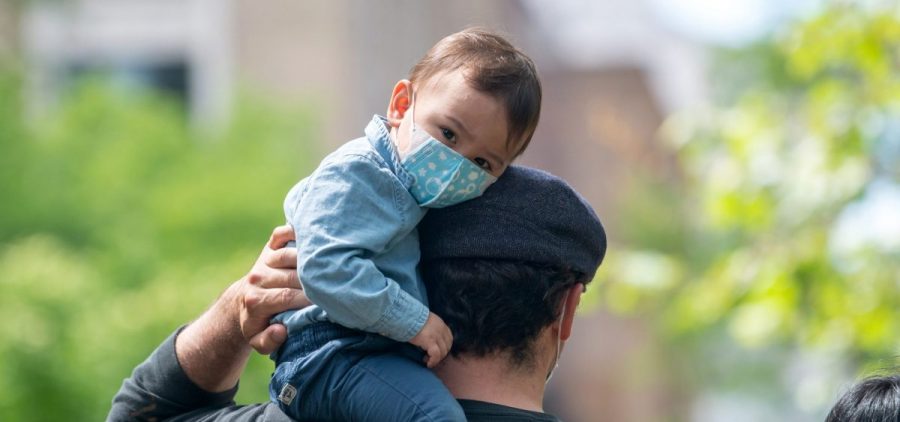 A child sits on his father's shoulder in New York City's Central Park in May 2020. The COVID-19 vaccine isn't presently available to those under 16, raising questions for parents and their kids.
