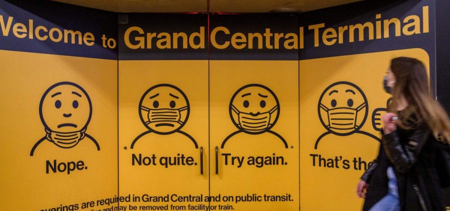 A woman walks past posters explaining mask requirements at Grand Central Terminal train station in New York City on Wednesday. Rules requiring masks on transit are unchanged by the Centers for Disease Control and Prevention's updated mask guidance for fully vaccinated people.