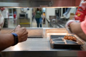 Cafeteria workers prepare food for students