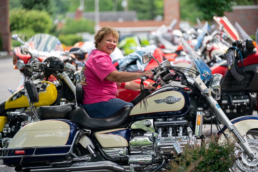Lori Holmes, a member and coordinator with the Valkyrie Riders Cruiser Club, poses for a portrait outside of the Ohio University Inn, on Sunset Dragon, her motorcycle, in Athens, Ohio, on Tuesday, June 15, 2021. [Joseph Scheller | WOUB]