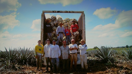 Mexican farm workers standing in front of harvesttruck