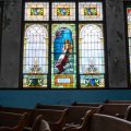 Doctor Tee Ford-Ahmed poses for a portrait next to the stain-glass window inside of the Mt. Zion Baptist Church that has since become the symbol for the church, in Athens, Ohio, on Wednesday, July 21, 2021. [Joseph Scheller | WOUB]
