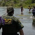 A Border Patrol agent watches as a group of migrants walk across the Rio Grande on their way to turning themselves in upon crossing the U.S.-Mexico border in Del Rio, Texas.