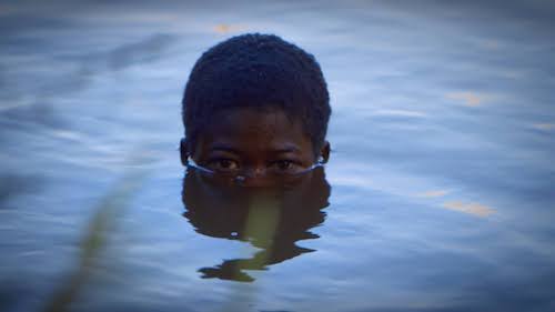 Boy in water, with just head to eyes peering out