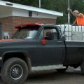 A man pours water from a water dispensary into the back of his truck
