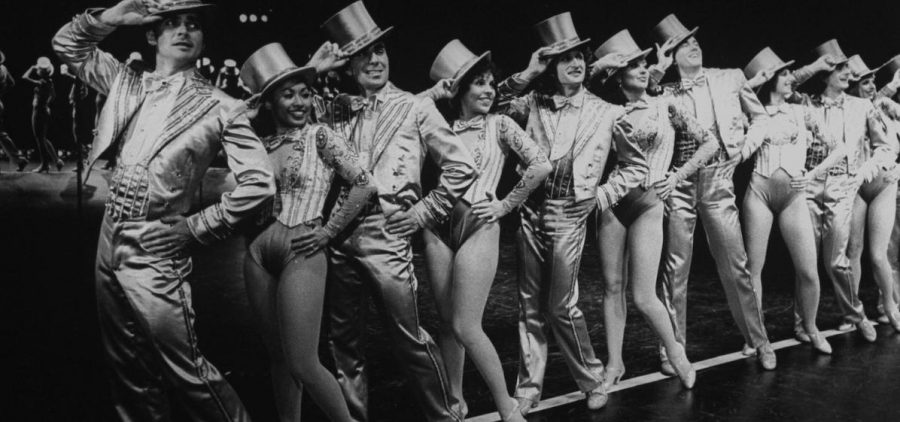 1940ish Broadway dancers lined up on stage tipping top hats