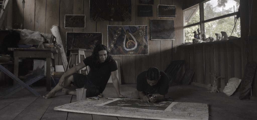 painter working on art on floor of rustic cabin