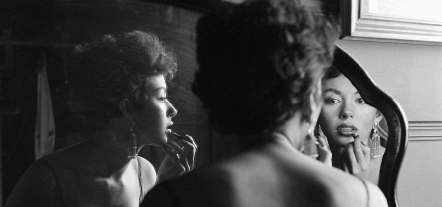 Portrait of film and Broadway actor Rita Moreno as she puts on makeup in the mirror, Hollywood, 1954.
