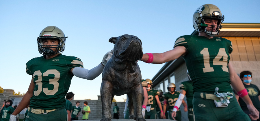 Two Athens players touching a statue of a bulldog